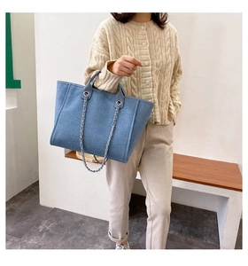 Blue denim tote bag detail featuring silver metal chain strap and dual handle design