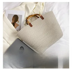 Detail view of woven tote bag with bamboo handle showing iPad and phone storage capacity