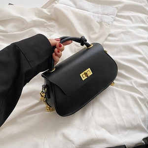 Close-up of black PU leather bag with golden square turn-lock and chain strap detail