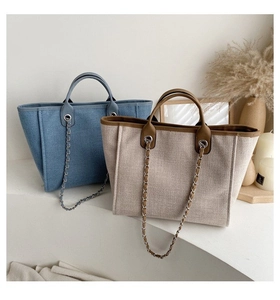 Close-up of canvas tote bag with leather trim and metallic chain strap detail