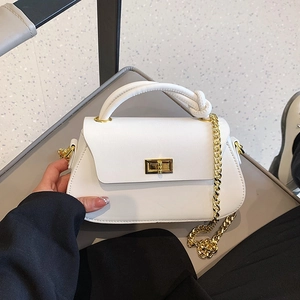 Detail of white PU leather crossbody bag featuring gold turn-lock and thick top handle