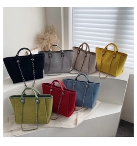 Close-up of colorful canvas tote bags showing textured fabric and metal chain straps