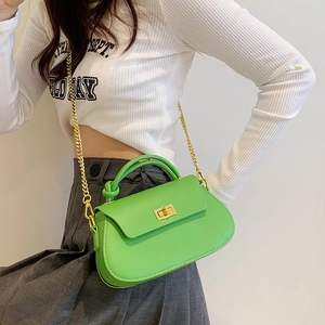 Model wearing a bright green crossbody bag with gold twist lock and chain strap detail