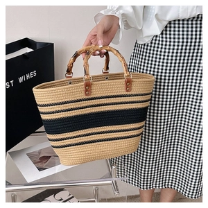 Detail of striped woven tote bag featuring vintage bamboo handles and leather accents