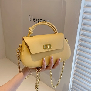 Detail of a beige leather crossbody bag featuring a golden twist lock and chain strap