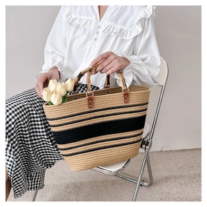 Detail of woven straw tote bag with black stripes, bamboo handle, and faux tulips inside