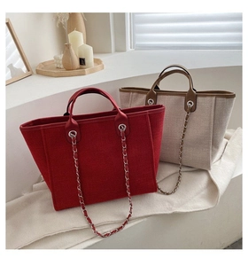 Detail of red and beige tote bags with silver chain straps in a minimalist lifestyle setting