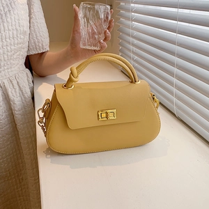 Close-up of bright yellow leather shoulder bag featuring gold twist lock and knot handle detail
