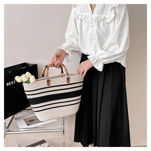 Detail of woven striped tote bag featuring natural bamboo handles and textured cotton fiber