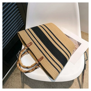 Detail of woven tote bag with bamboo handles and black stripes on a white chair