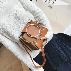 Close-up of brown vintage crossbody bag with large gold metal handle and chain strap