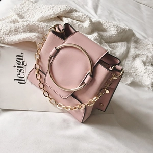 Pink faux leather crossbody bag with bold gold ring decoration and chain strap