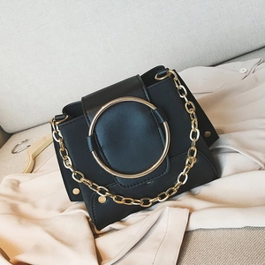 Detail of black crossbody bag with large gold metal ring and chunky chain strap
