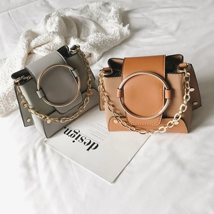 Detail of square crossbody bags with large gold metal handles and chain straps