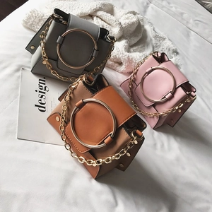 Detail view of retro crossbody bags with metallic round handles and golden chain straps