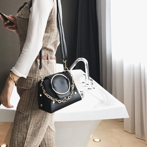 Detail of black matte leather crossbody bag with gold ring and chunky chain hardware