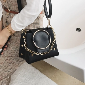 Detail of crossbody bag with vintage gold ring hardware and decorative metal chain