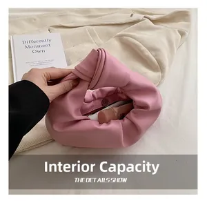 Internal capacity of pink knotted leather handbag shown with cosmetics and books
