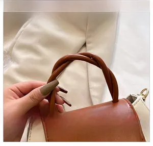 Detailed macro view of the cream and brown contrast handbag with spiral twisted handle