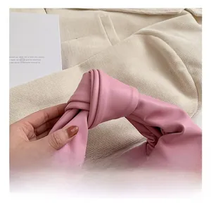 Detailed close-up of a pink pleated handbag featuring a stylish knotted handle design