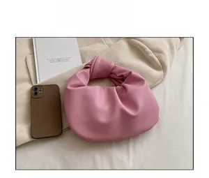 Detailed close-up of pink ruched handbag with knotted handle and minimalist pleated design