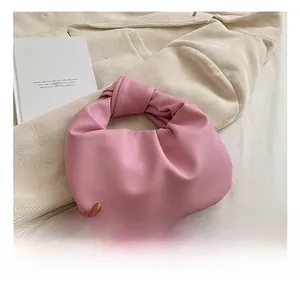Detail shot of a pink knotted handle bag with soft pleated cloud design on velvet background