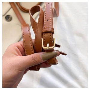 Macro shot of brown faux leather handbag strap with adjustable gold buckle detail