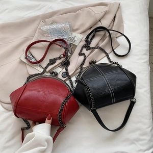 Quilted shell bags in black and red with metal ball clasp and chain straps on white fabric