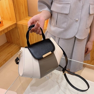 Close-up of tricolor leather handbag with adjustable strap and gold metal hardware detail