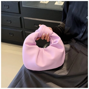 Close-up of lavender pleated leather handbag featuring a stylish knotted handle detail