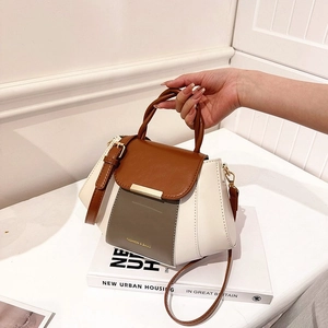 Detail of tricolor leather handbag with woven handle and elegant gold hardware accents