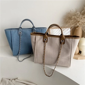 Minimalist woven tote bags in blue and beige with leather handles and metal chain straps