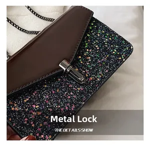 Détail du fermoir tournant argenté sur cuir brun et tissu à paillettes de sac
