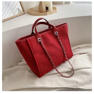 Red textured tote bag with metal chain strap and top handles for casual daily wear