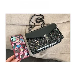 Détail d'un mini sac à paillettes noires à côté d'un smartphone pour la taille