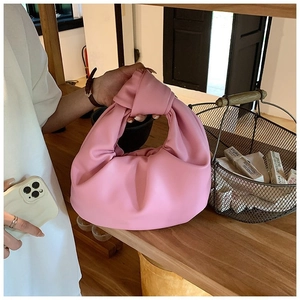 Detailed view of a pink knotted handle handbag with ruched faux leather crescent shape