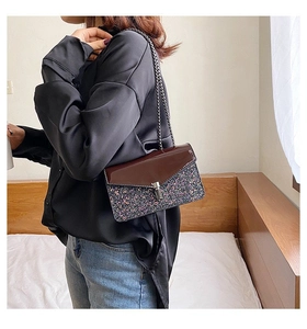 Détail du sac à bandoulière en paillettes mauves avec rabat en cuir verni brun et chaîne