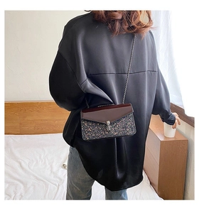 Détail du sac à bandoulière à paillettes avec rabat marron foncé et chaîne argentée