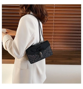 Vue latérale du sac bandoulière pailleté noir porté sur une veste blanche