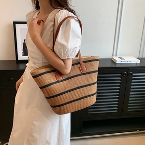 Detailed view of large capacity striped woven tote bag with brown leather shoulder straps