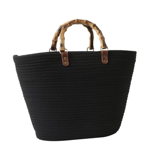Minimalist black woven tote bag featuring natural bamboo handles and spacious interior