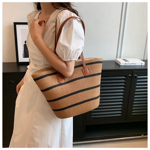 Detail of woven straw tote bag with black stripes and dark brown PU leather straps