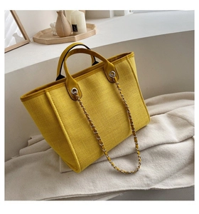 Bolso tote de lona amarillo brillante con cadena sobre un fondo de decoración minimalista