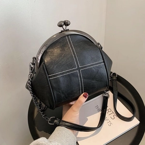 Minimalist black shell-shaped crossbody bag with white contrast stitching and chain strap