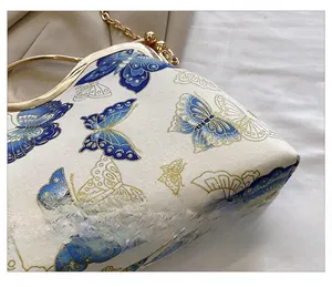 Detail of white woven fabric featuring blue butterfly patterns and gold chain strap