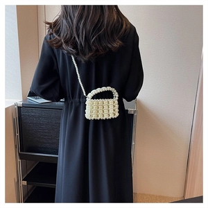 Detail einer handgefertigten Perlenhandtasche mit Rosenstruktur auf einem schwarzen Kleid