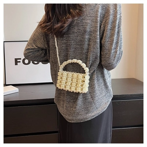 Detail der cremeweißen Perlenhandtasche mit 3D-Rosenrelief und langem Perlen-Schultergurt