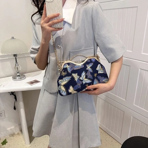 Detail of blue satin handbag with gold butterfly pattern and vintage metal clasp