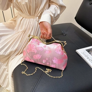 Detail of pink satin bag with floral embroidery and golden metal handle held by model