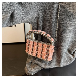 Detail der rosa geblümten Perltasche mit Silberkette auf einem Strickpullover